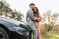 Romantic ÃÂouple dressed in tracksuits hugs while standing near car in nature. Royalty Free Stock Photo
